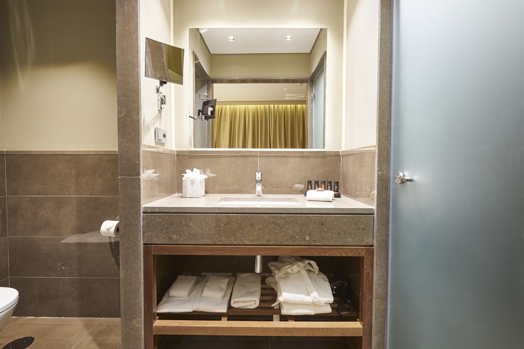 A modern bathroom with a stone vanity, large mirror and open towel shelves