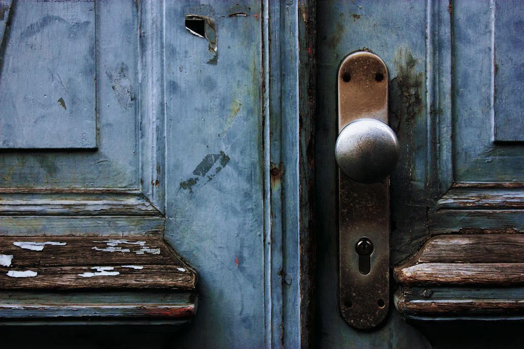 A close-up of a sturdy door handle and lock on a painted wooden door